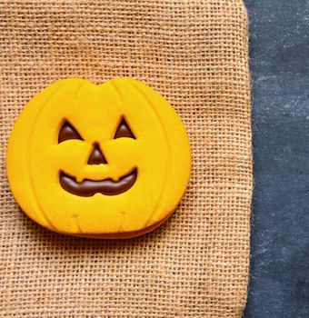 Halloween cookies with pumpkin shape on blackboard.