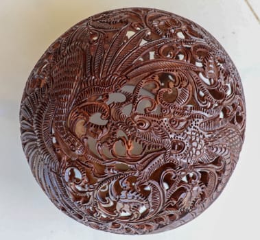 Close up ornamental shell for candle. Carved Souvenir from Coconut. Traditional handicraft on Bali, Indonesia. Hand carved ornaments with animal and plant motifs on the coconut shell. Mystical dragon.