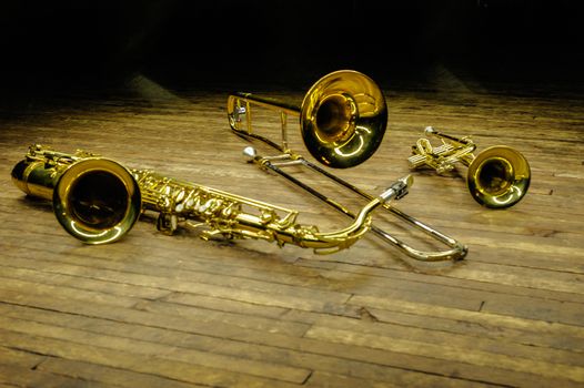 Yellow brass and wind instruments - saxophone, trombone, trumpet on stage with backlight