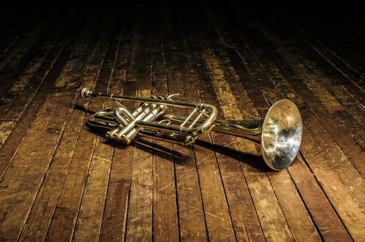 white brass trumpet lies on a wooden stage