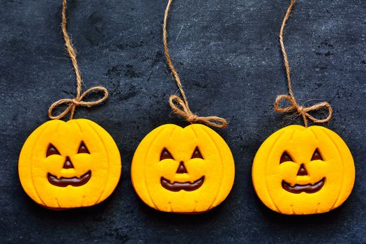 Halloween cookies with pumpkin shape on blackboard.