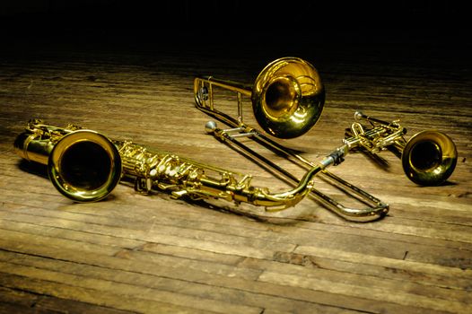 Yellow brass and wind instruments - saxophone, trombone, trumpet on a wooden stage with backlight