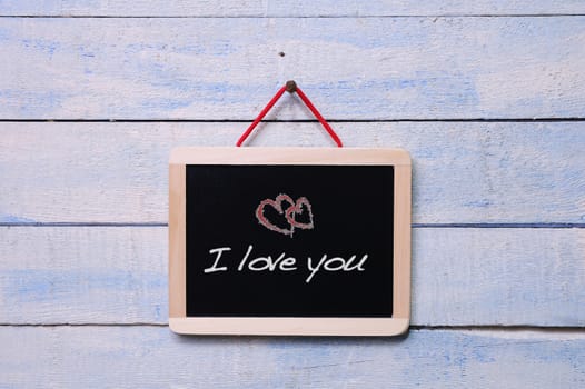 Blackboard on a old wooden wall with phrase, I love you.