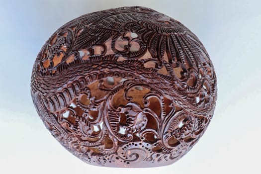 Close up ornamental shell for candle. Carved Souvenir from Coconut. Traditional handicraft on Bali, Indonesia. Hand carved ornaments with animal and plant motifs on the coconut shell. Mystical dragon.