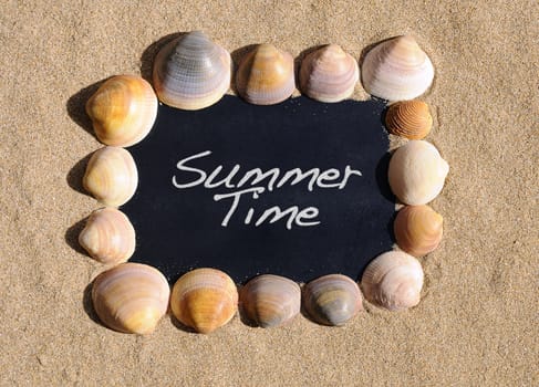Blackboard on beach sand with the phrase summer time.