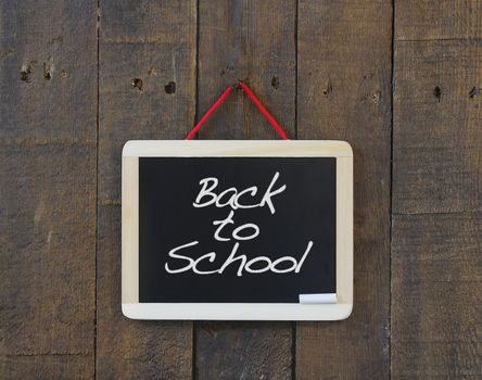 Blackboard hanging on a old wooden wall with Back to school.