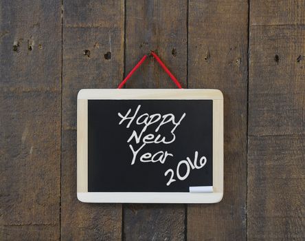 Blackboard hanging on a old wooden wall with Happy New Year.