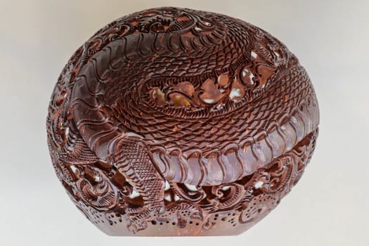 Close up ornamental shell for candle. Carved Souvenir from Coconut. Traditional handicraft on Bali, Indonesia. Hand carved ornaments with animal and plant motifs on the coconut shell. Mystical dragon.