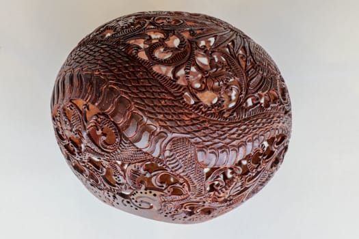 Close up ornamental shell for candle. Carved Souvenir from Coconut. Traditional handicraft on Bali, Indonesia. Hand carved ornaments with animal and plant motifs on the coconut shell. Mystical dragon.