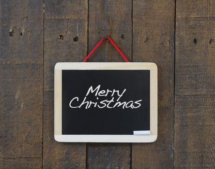 Blackboard hanging on a old wooden wall with Merry Christmas.
