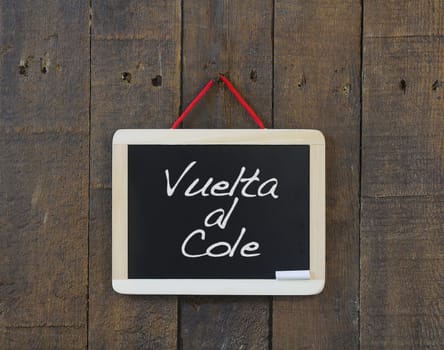 Blackboard hanging on a old wooden wall with Back to school.