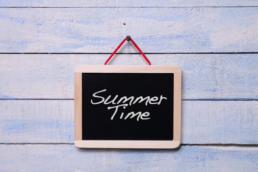 Blackboard hanging with Summer time phrase on wooden wall.