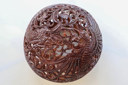 Close up ornamental shell for candle. Carved Souvenir from Coconut. Traditional handicraft on Bali, Indonesia. Hand carved ornaments with animal and plant motifs on the coconut shell. Mystical dragon.