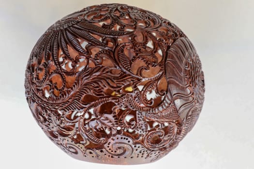 Close up ornamental shell for candle. Carved Souvenir from Coconut. Traditional handicraft on Bali, Indonesia. Hand carved ornaments with animal and plant motifs on the coconut shell. Mystical dragon.