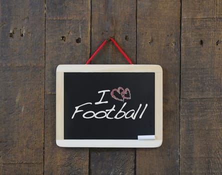 Blackboard hanging on a old wooden wall with word football.