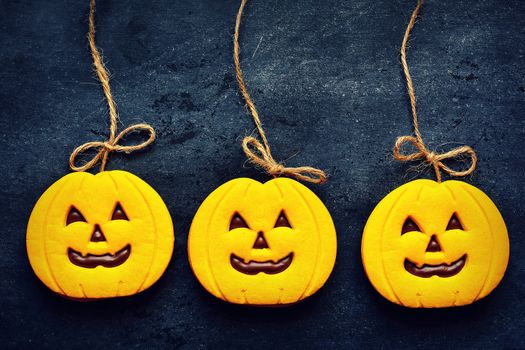 Halloween cookies with pumpkin shape on blackboard.