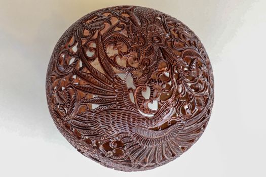 Close up ornamental shell for candle. Carved Souvenir from Coconut. Traditional handicraft on Bali, Indonesia. Hand carved ornaments with animal and plant motifs on the coconut shell. Mystical dragon.