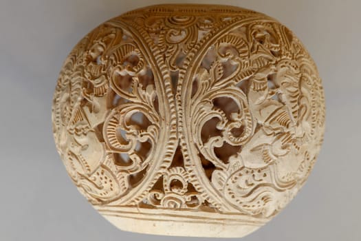 Close up of ornamental shell for candle. Hand carved decorative ornaments and motif of Hindu God Ganesha.Carved souvenir from white coconut. Traditional handicraft on Bali, Indonesia.