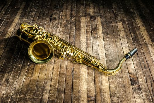 yellow jazz musical instrument saxophone lies on a wooden brown stage