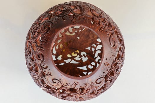 Close up ornamental shell for candle. Carved Souvenir from Coconut. Traditional handicraft on Bali, Indonesia. Hand carved ornaments with animal and plant motifs on the coconut shell. Mystical dragon.