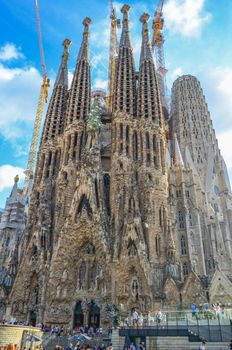 La Sagrada Familia with construction cranes on a blue sky fon in Barcelona, ​​Spain