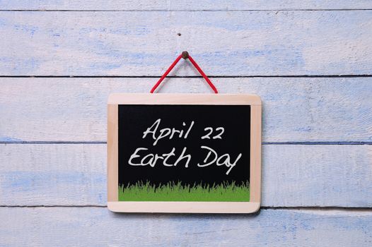 Blackboard hanging on a old wooden wall with Earth Day.