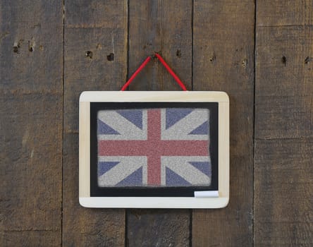 Blackboard hanging on a old wooden wall with UK flag.