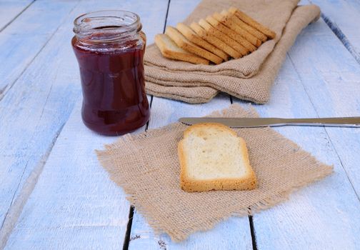 Preparing toast with strawberry jam on wooden table