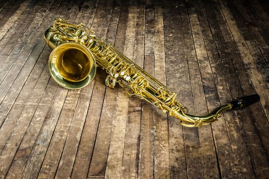 yellow saxophone musical instrument lies on a wooden floor