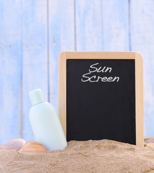 Jar of sunscreen on the beach sand and blackboard.