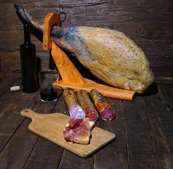 Iberian ham and Spanish sausages on wooden table.