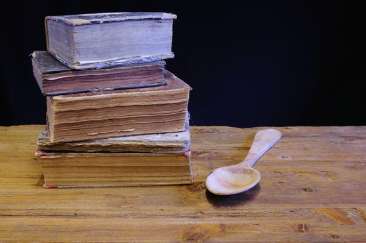 Old cookbook on wooden table with a wooden spoon