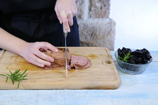 Cutting foie gras on wooden table in the kitchen