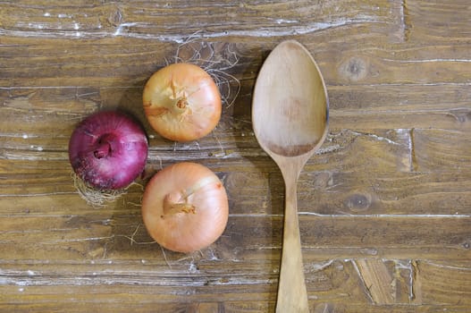 Onions over the kitchen table and wooden spoon.