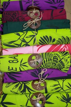 Batik cloth cloth for sale rolled up in market. Balinese art and culture. Close up of rolled colorful sarong. Colorful fabric rolls. Traditional Hindu clothing on Bali island. Sarung ready for sell.