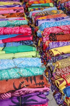 Batik cloth cloth for sale rolled up in market. Balinese art and culture. Close up of rolled colorful sarong. Colorful fabric rolls. Traditional Hindu clothing on Bali island. Sarung ready for sell.