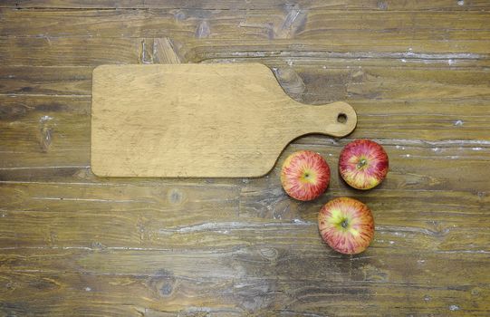 Cutting board in cooking with the three apples.