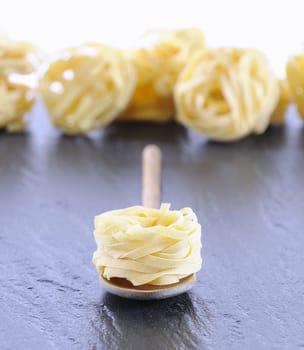 Tagliatelle in a spoon on the kitchen table.