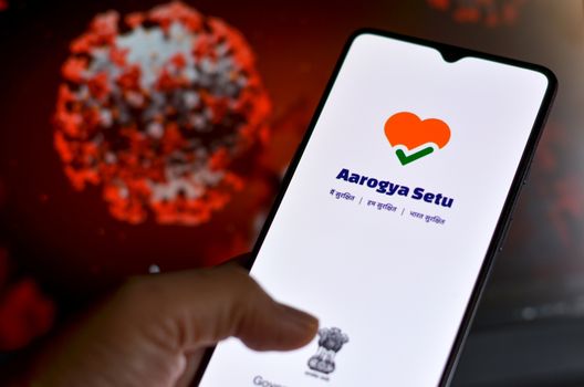 New Delhi, India, 2020. Aarogya Setu app, developed by government of India to track the Covid-19 status, Logged in on a mobile infront of a screen showing microscopic 3D illustration of Corona Virus
