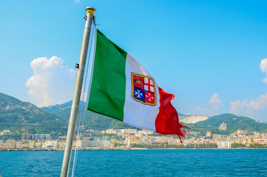 Civil ensign of Italy. National Flag on the background of the sea and mountains