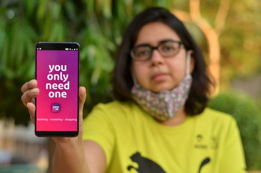 New Delhi, India, 2020. Girl wearing a face mask showing SBI bank app during Corona Virus (Covid-19) disease pandemic. People are encouraged to not visit the bank but do digital banking transactions