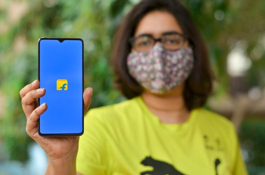 New Delhi, India,2020. Girl wearing mask show Flipkart app on mobile under home quarantine during Corona virus (Covid-19) disease pandemic. Only delivery of essentials are allowed during the lockdown
