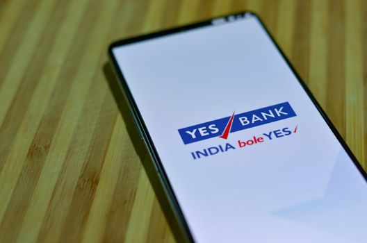 New Delhi, India, 2020. Flat lay Yes bank app on mobile phone screen against a wooden board background. People are encouraged to not visit the bank but do digital banking transactions during lock down