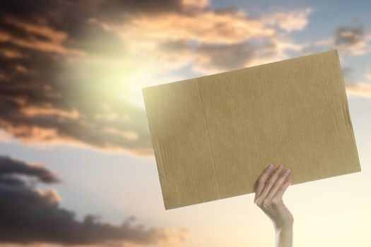 Woman's hands holding a blank placard to put the text at protesting with sky and sunlight background.