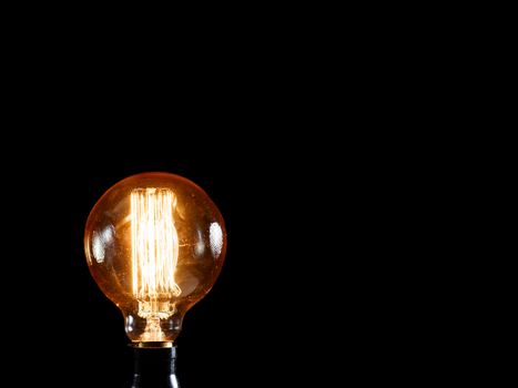 Vintage Edison lamp on black background. Creative idea concept.