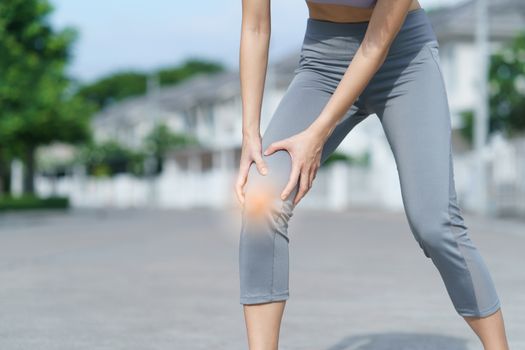 Woman holds her hands to the knee, pain in the knee highlighted in red, medicine, massage concept.