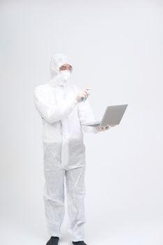 man scientist wearing biological protective uniform suit clothing, mask, gloves spraying sanitizer on computer for sanitizing virus bacteria