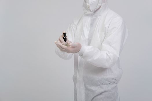 man doctor wearing biological protective uniform suit clothing, mask, gloves washing hand with sanitizer dispenser for sanitizing virus bacteria