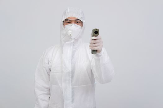 doctor man wearing biological protective uniform suit clothing, mask, gloves measuring body temperature with infrared forehead thermometer gun