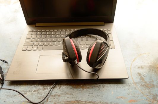 Portable over-ear Binaural Sound USB Headset with Microphone Noise Cancelling and Ultrasonic Volume Adjuster Headphone for Computer, Skype placed on laptop on morning sunlight. Music Background.